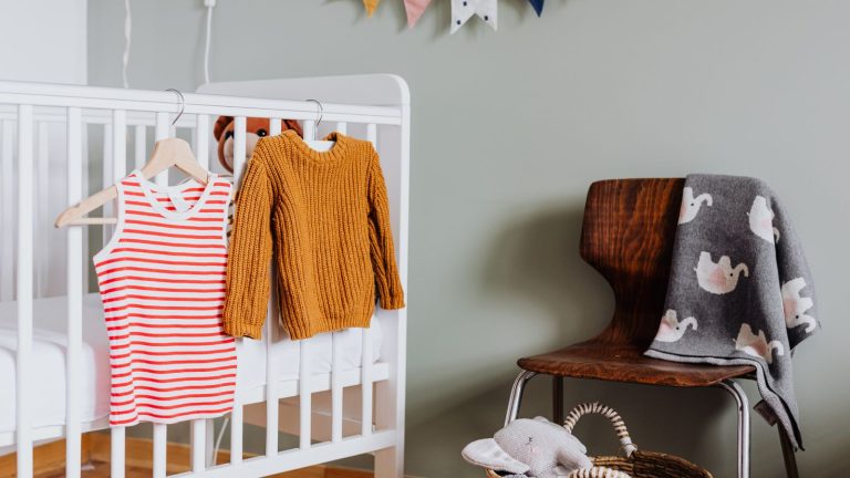 Chambre de bébé aux murs sauge avec lit blanc et parquet clair