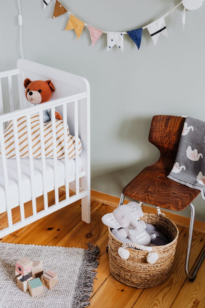 Chambre de bébé moderne aux tons sauge, lit blanc et bois clair