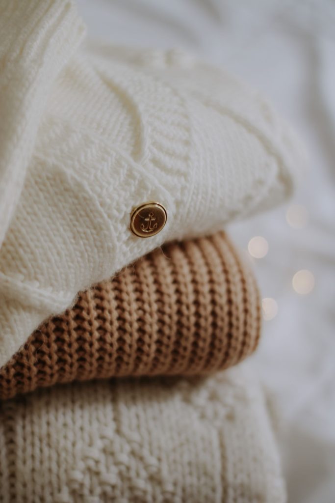Deux gilets en maille pour bébé, crème et caramel, posés l’un sur l’autre