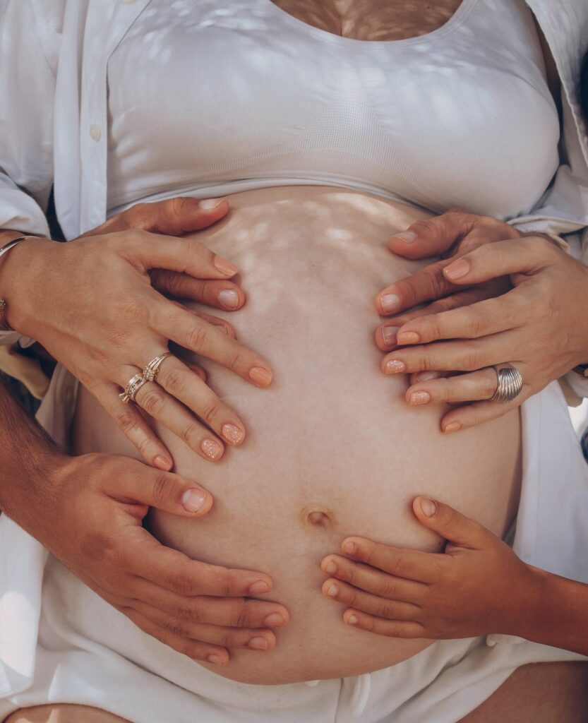 Mains de la famille posées sur le ventre d'une femme enceinte, dans l'attente de bébé