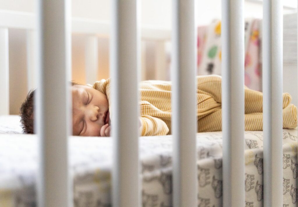 Bébé endormi paisiblement dans son lit à barreaux, en pyjama, sans couverture ni oreiller