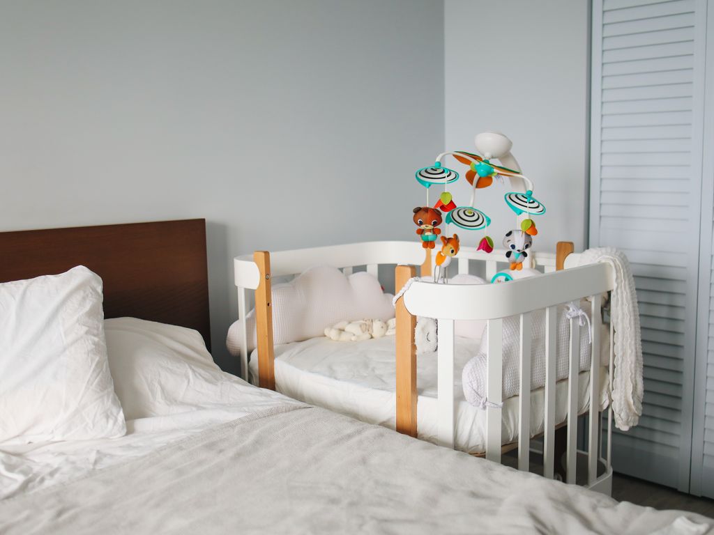 Chambre de bébé claire et moderne avec un lit cododo en bois et blanc