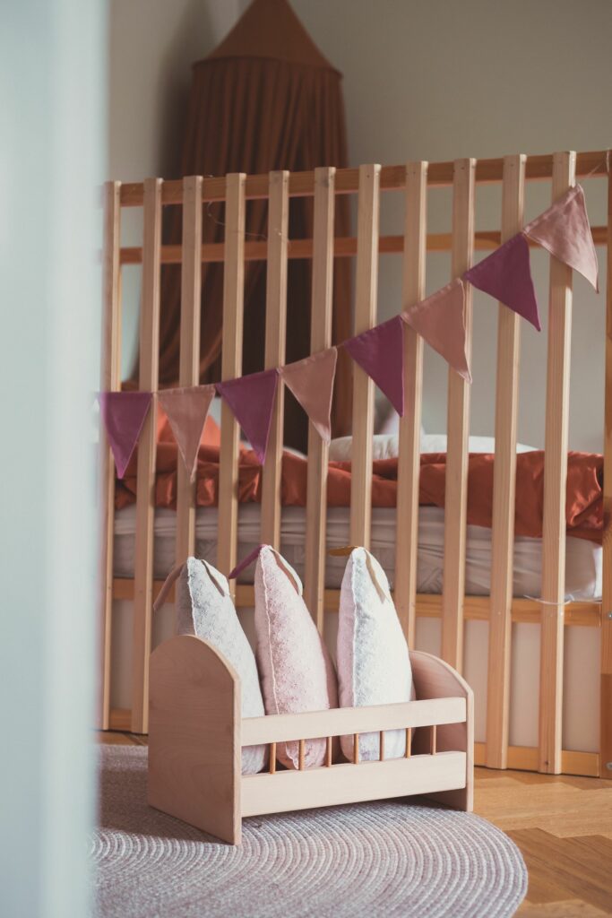 Chambre de bébé fille bohème avec fanions et coussins vieux rose