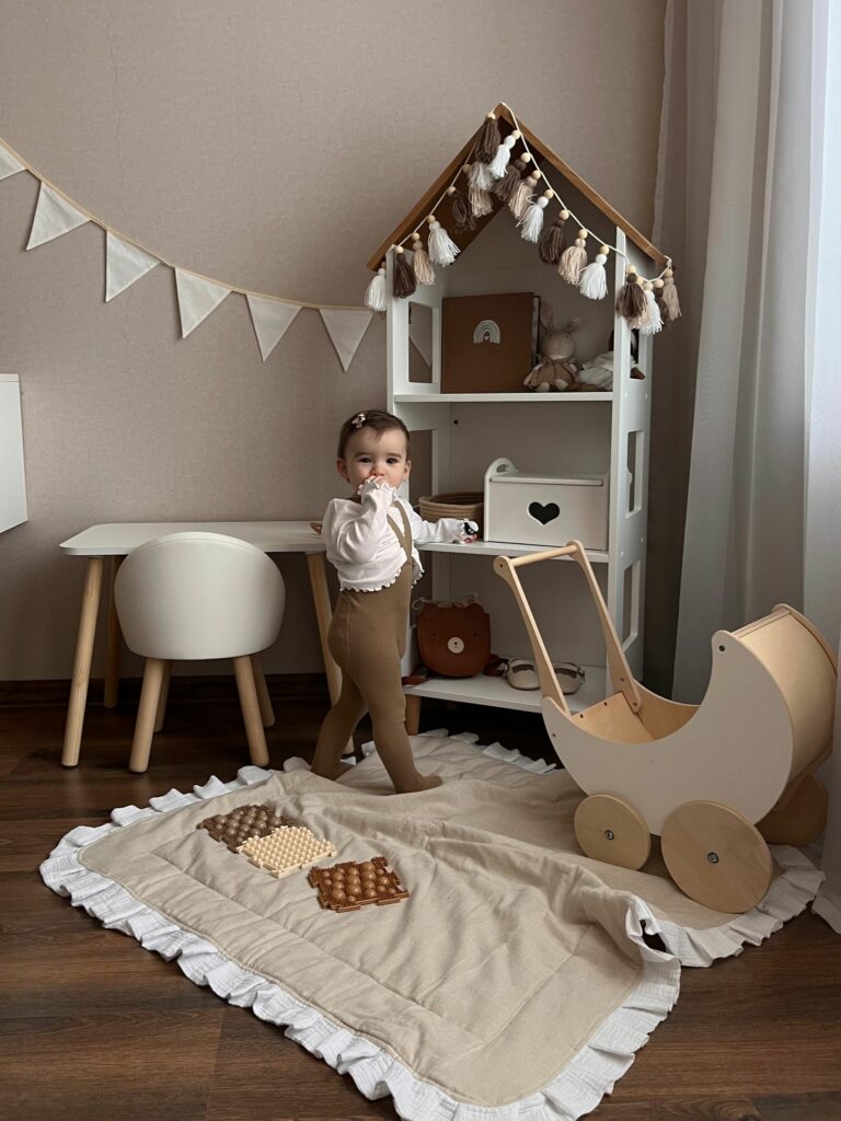 Chambre de bébé fille aux tons naturels avec maison de poupée en bois