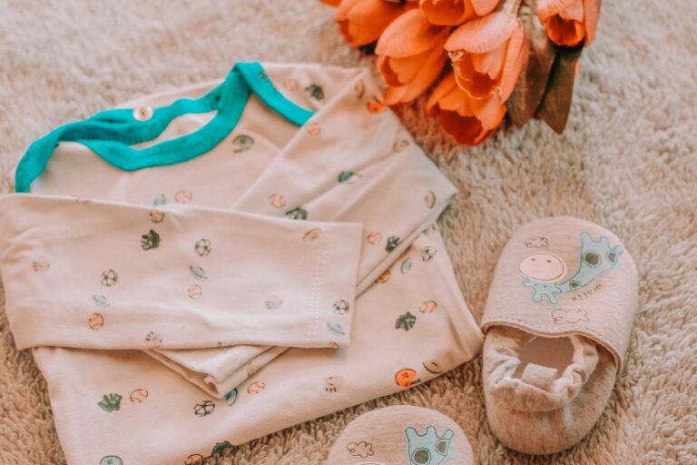 Pyjama, chaussons et petites affaires de bébé pliés sur une couverture, prêts pour la naissance