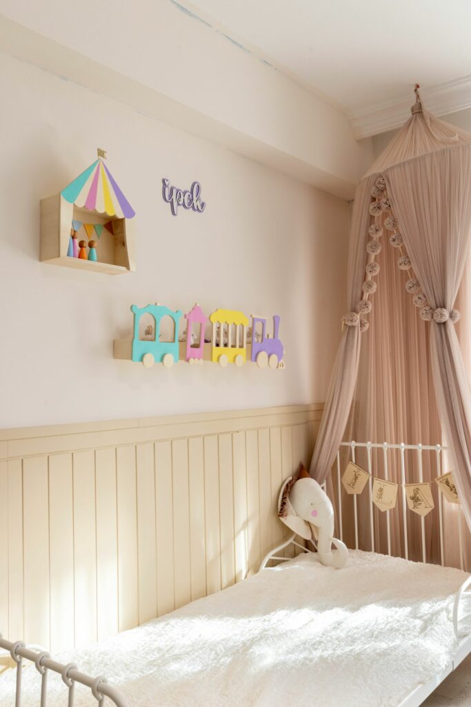Ciel de lit et guirlande dans une chambre de bebe aux tons roses