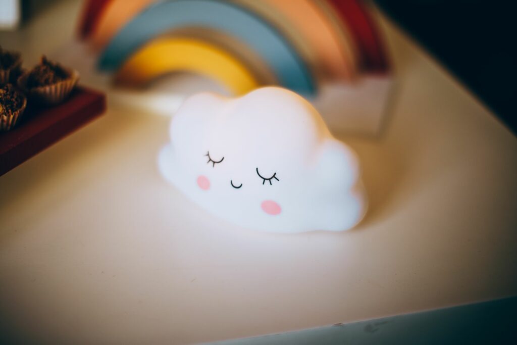 Veilleuse en forme de nuage lumineuse posée sur une table dans une chambre de bébé