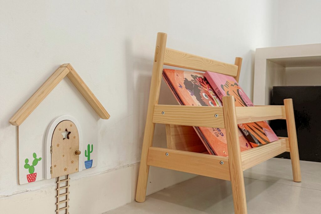 Coin lecture d'une chambre de bébé : petite bibliothèque en bois avec des livres à hauteur d'enfant