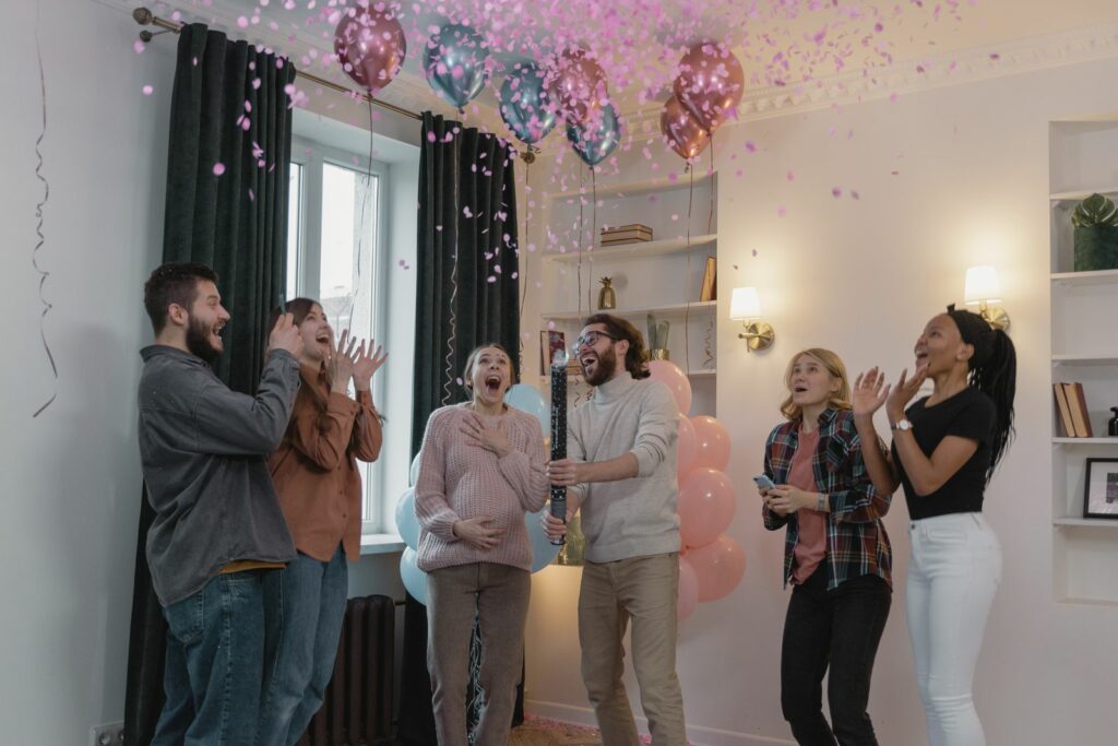 Proches réunis fêtant une gender reveal avec des ballons roses et bleus