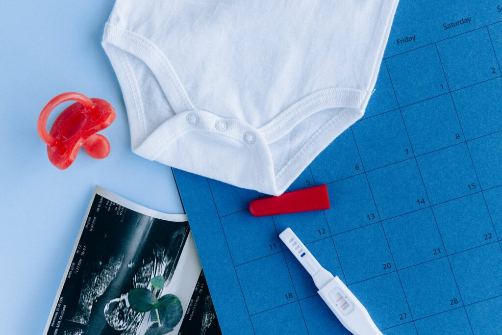Calendrier, test de grossesse, échographie et body posés à plat