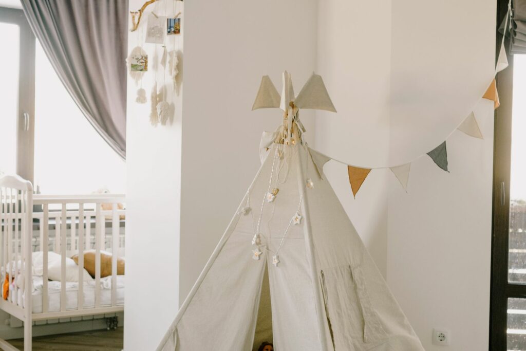 Coin d'éveil clair d'une chambre de bébé avec tipi en lin et tapis