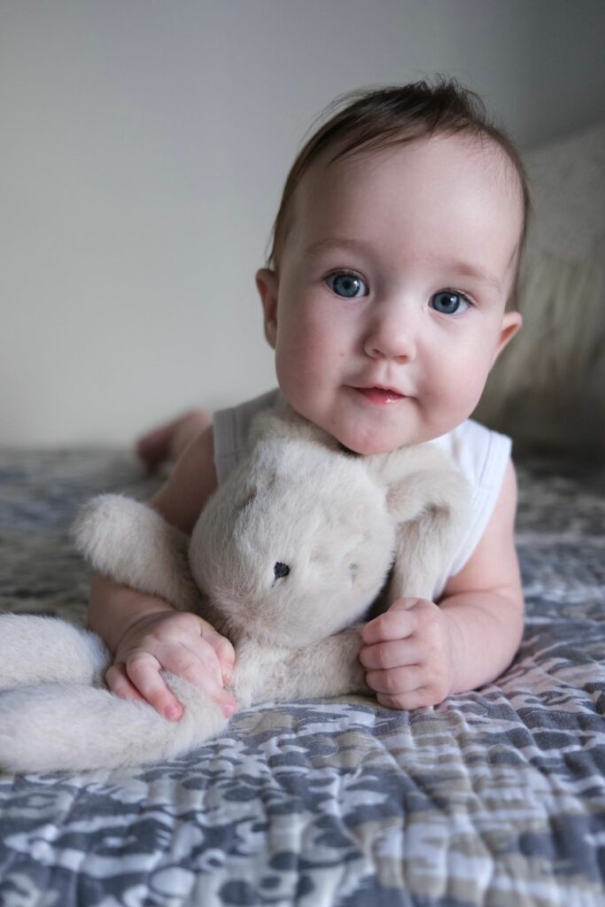 Bébé serrant son doudou en peluche sur son lit