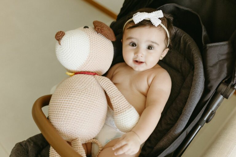 Bébé installé dans une poussette moderne avec un doudou tricoté