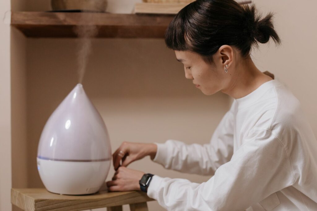 Femme réglant un humidificateur à vapeur froide dans une pièce claire