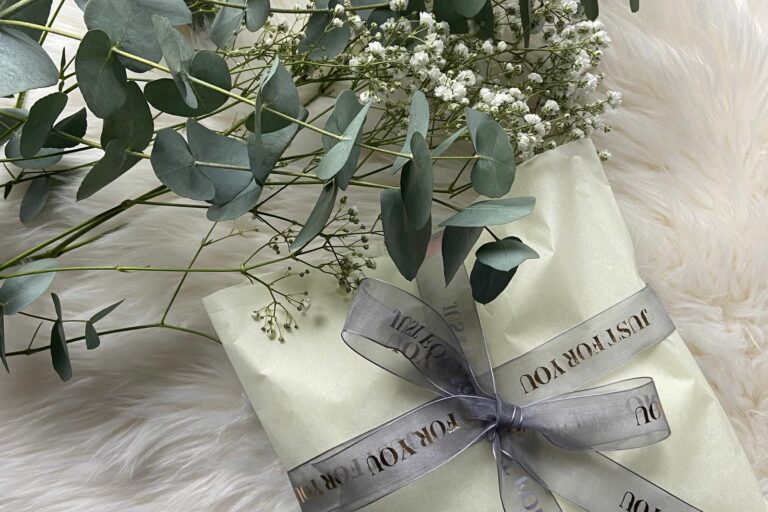 Cadeau de naissance emballé avec un ruban et un brin d'eucalyptus
