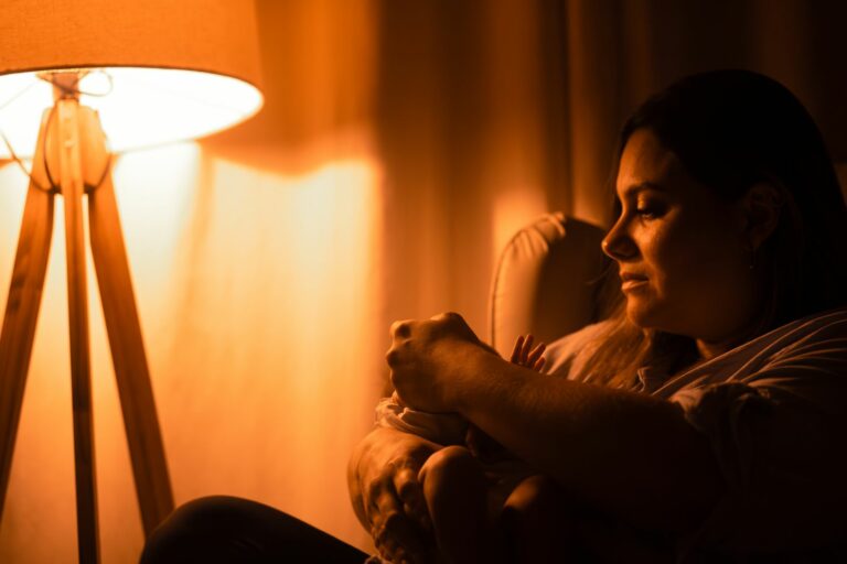 Maman tenant son bébé le soir dans la lumière douce et chaude d'une lampe, ambiance apaisante