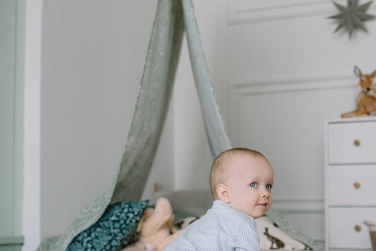 Bébé curieux assis au sol dans une chambre moderne, près d'une commode et d'un tipi