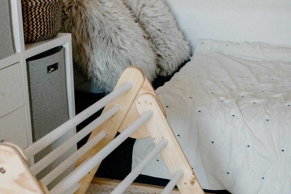 Chambre de bébé scandinave avec un lit au sol (coin nuit) et un triangle de motricité (coin éveil)