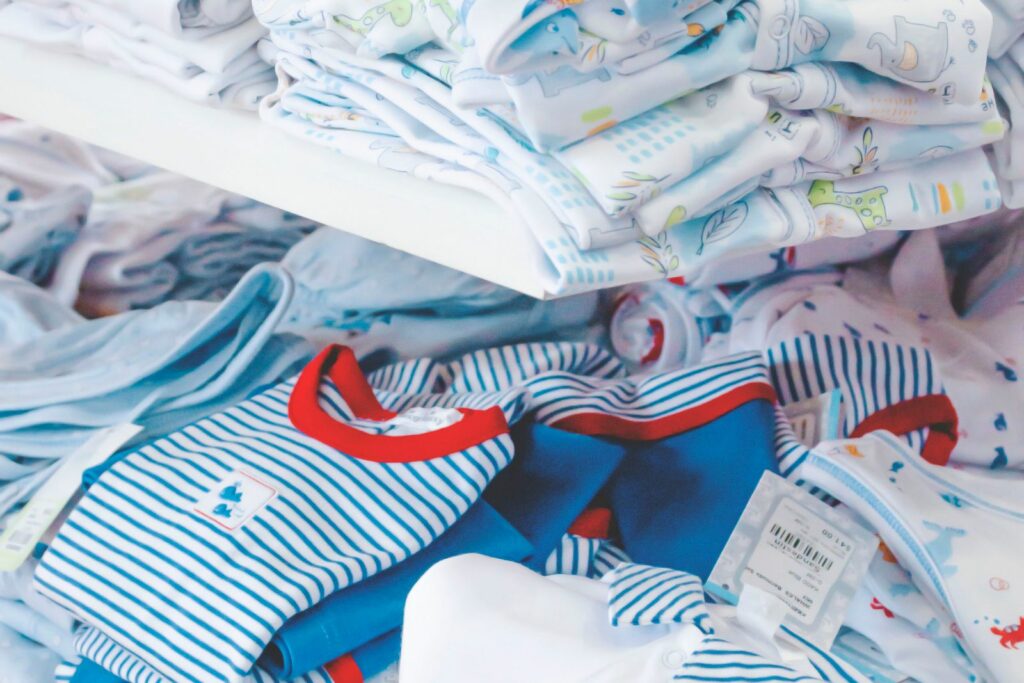 Piles de vêtements de bébé en rayon, illustrant le risque d'en acheter trop