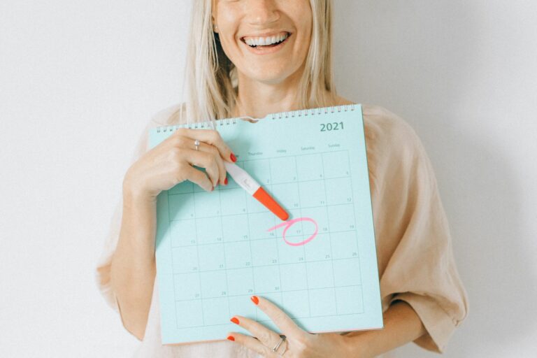 Femme enceinte souriante tenant un calendrier avec une date entourée