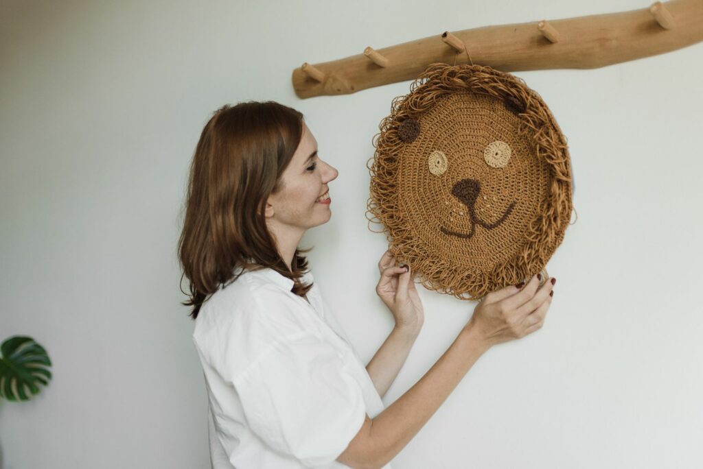 Femme accrochant une décoration murale lion en crochet dans une chambre claire