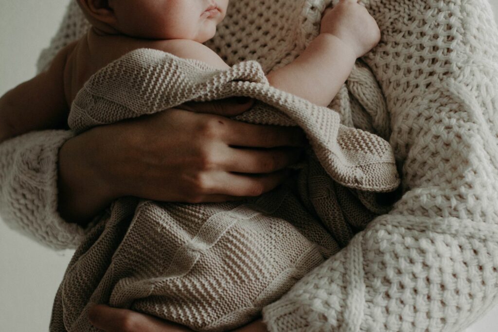 Parent serrant son nouveau-né enveloppé dans une couverture en maille douce