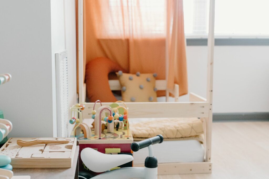 Lit au sol pour bébé : matelas au ras du sol sous un cadre maison en bois, ciel terracotta, chambre moderne