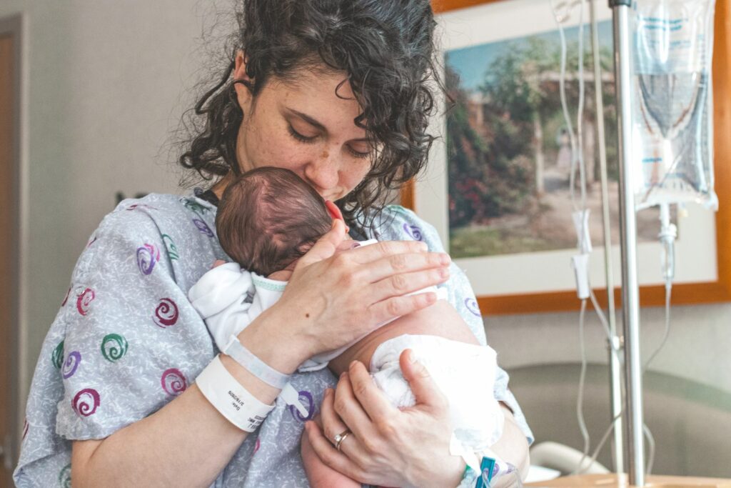 Maman en chemise de maternité embrassant son nouveau-né emmailloté