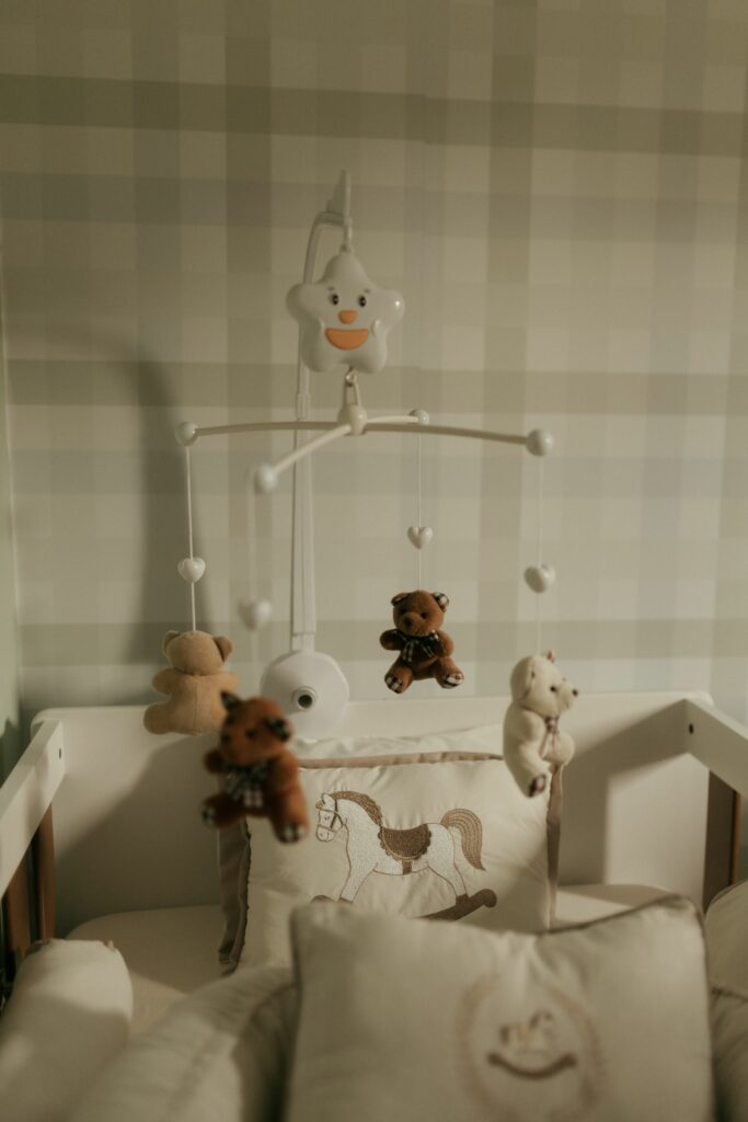 Mobile animalier avec oursons au-dessus d'un lit de bebe, ambiance sauge