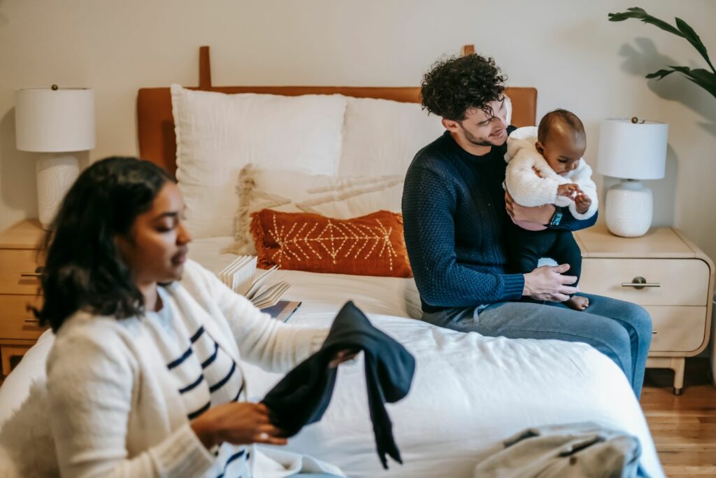 Vêtements de bébé rangés : hauts sur un portant en bois et pile de vêtements pliés, tons neutres