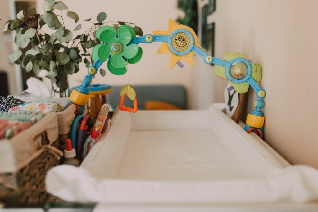 Plan à langer sur une commode : matelas à langer, arche de jeu et panier de produits de soin
