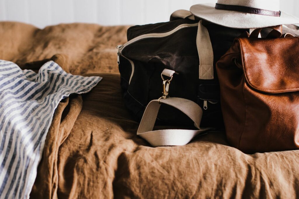 Sac de voyage et sac à main prêts sur un lit, valise de maternité préparée à l'avance