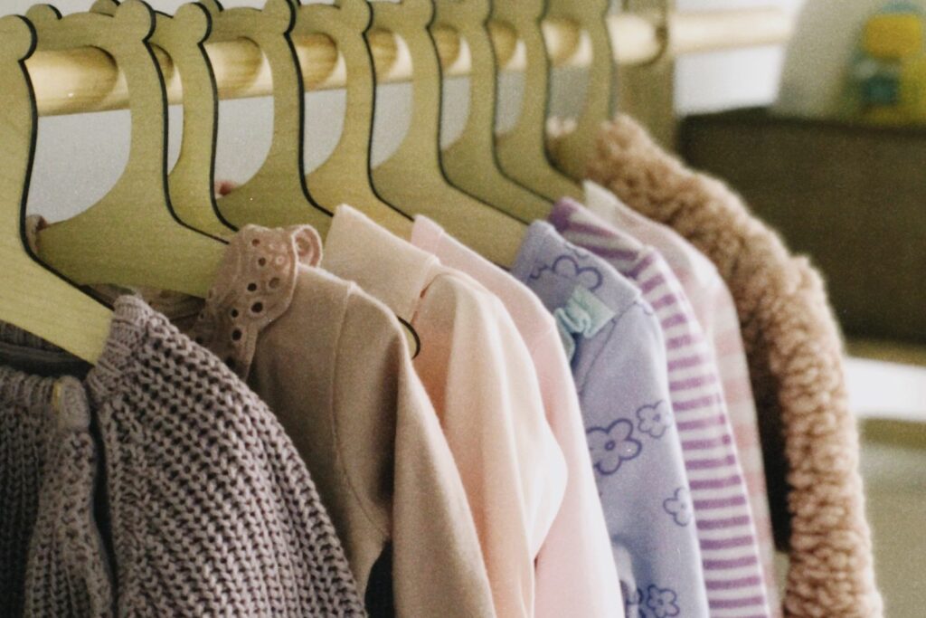 Petits vêtements de bébé suspendus sur des cintres en bois dans une penderie