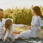 Une petite fille pointe du doigt l'échographie que tient sa maman enceinte, lors d'un pique-nique en famille dans l'herbe