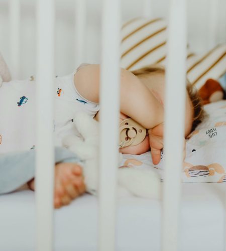 A baby peacefully sleeping with a pacifier in a cozy crib with plush blankets.